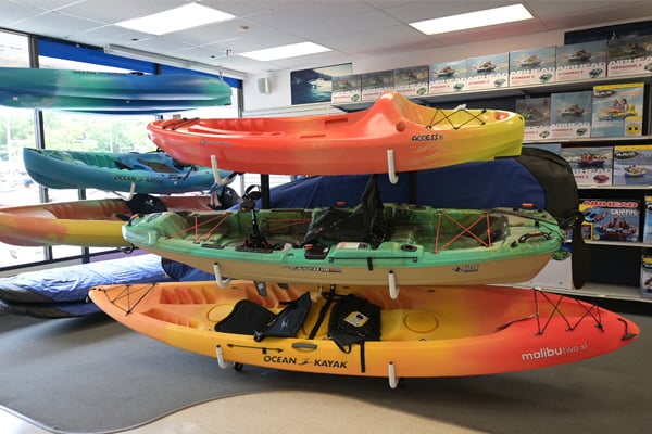 olorful kayaks hang on a custom-designed retail display fixture in an outdoor goods store.