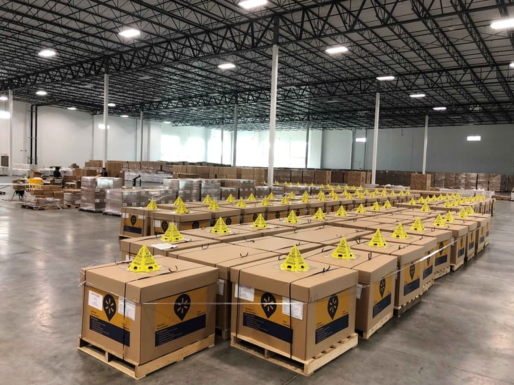 Large boxes with retail signage components for store navigation are sitting on the floor in a warehouse facility, waiting to be shipped.